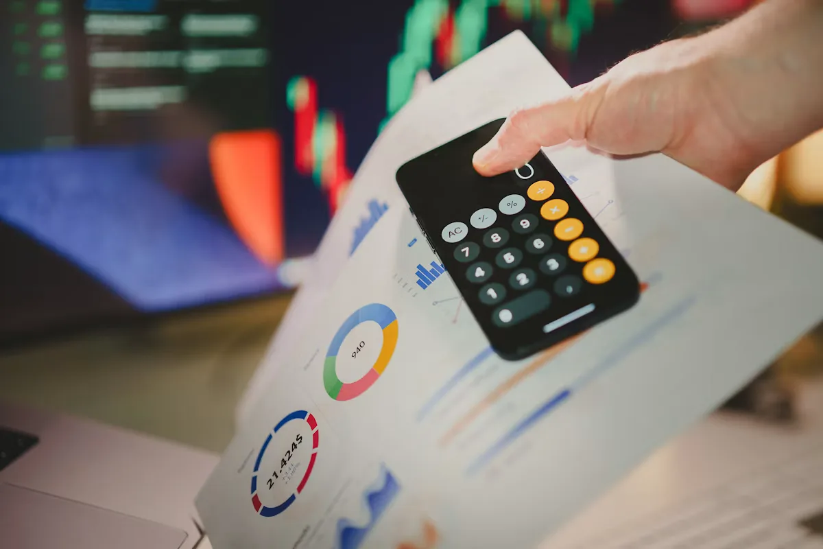 A hand holding a calculator over a piece of paper