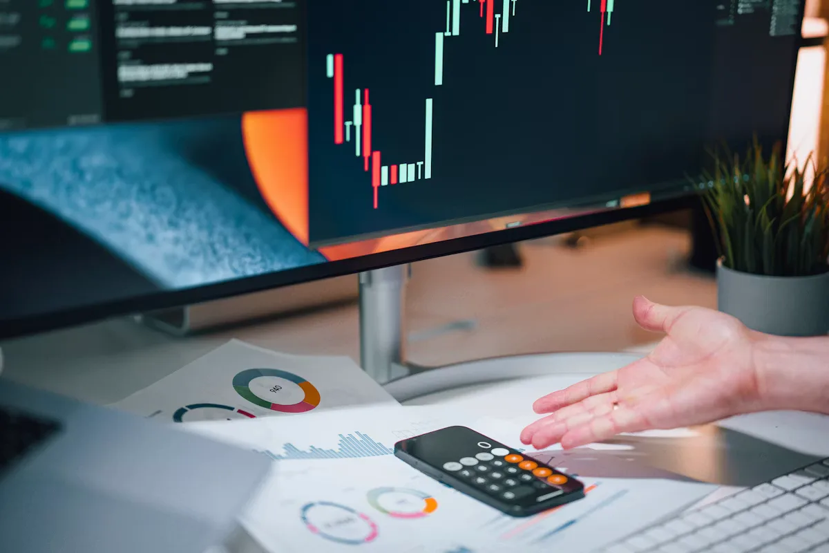 A person pointing at a calculator on a desk